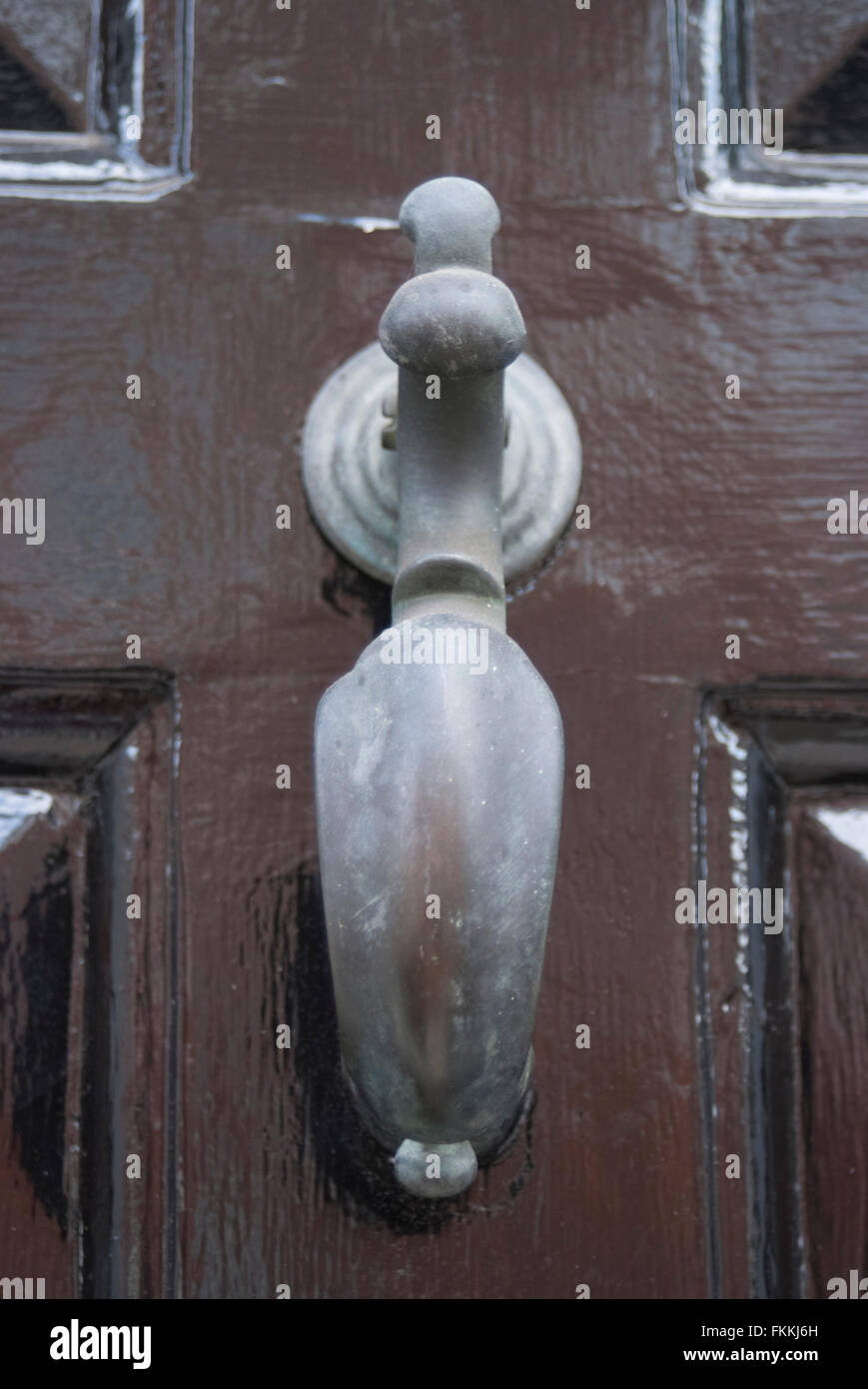 Eine alte Mode-Türklopfer an einer braunen Holz-Glas-Tür eines Wohnhauses. Stockfoto