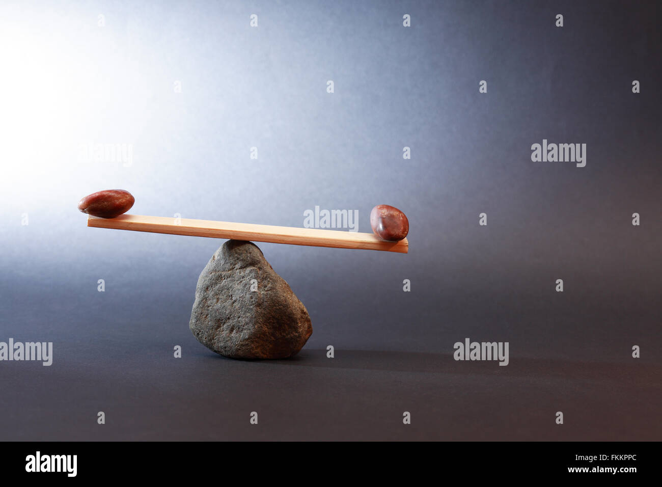 Balance-Konzept. Wippe aus Steinen und Holzbrett hergestellt Stockfoto