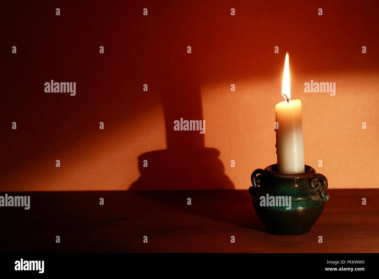 Anzünden der Kerze im Leuchter mit großer Schatten an der Wand Stockfoto