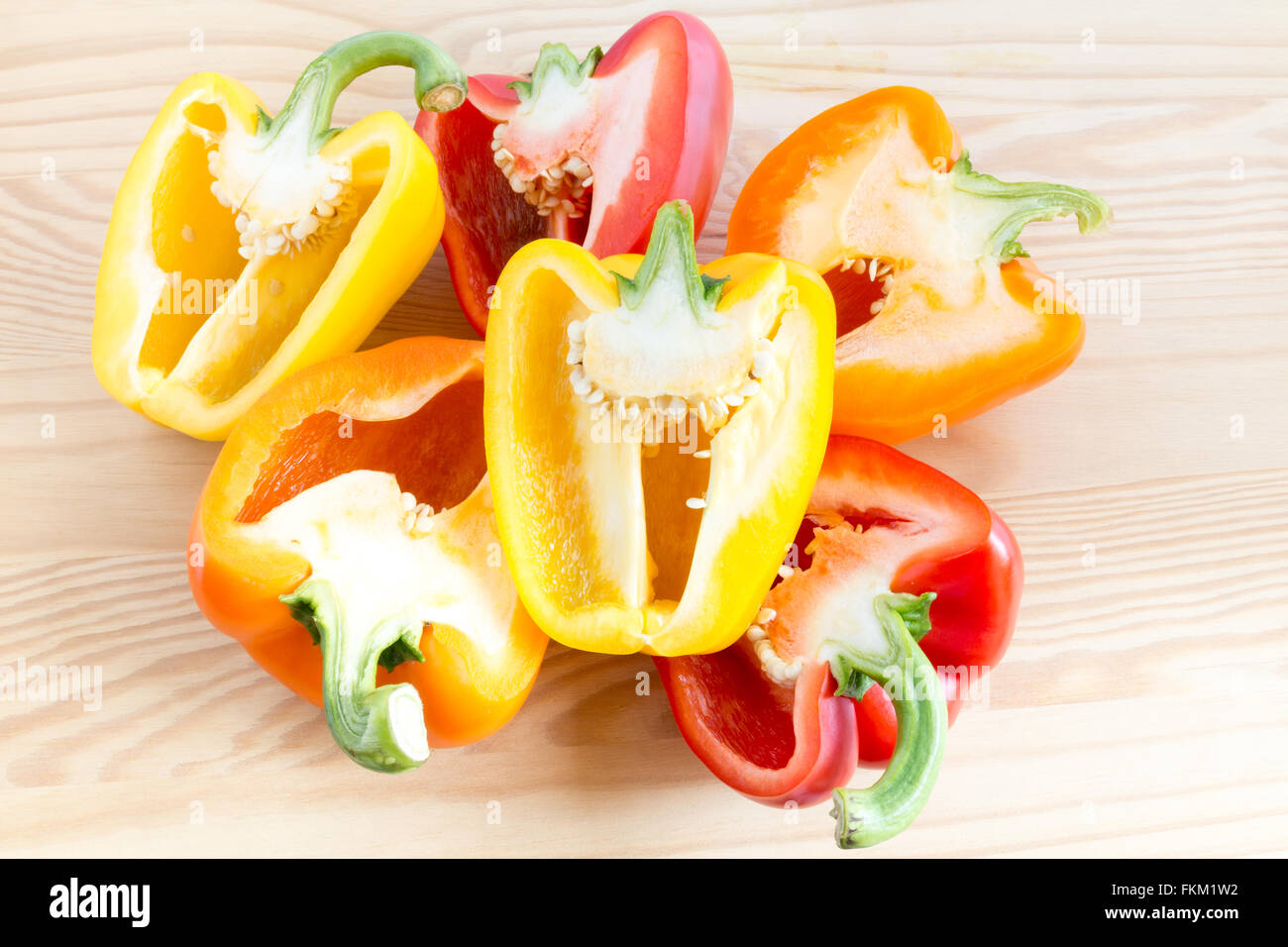 Stapel von drei halbierte Paprika in verschiedenen Farben, Orange, gelb und rot auf Schneidebrett Stockfoto