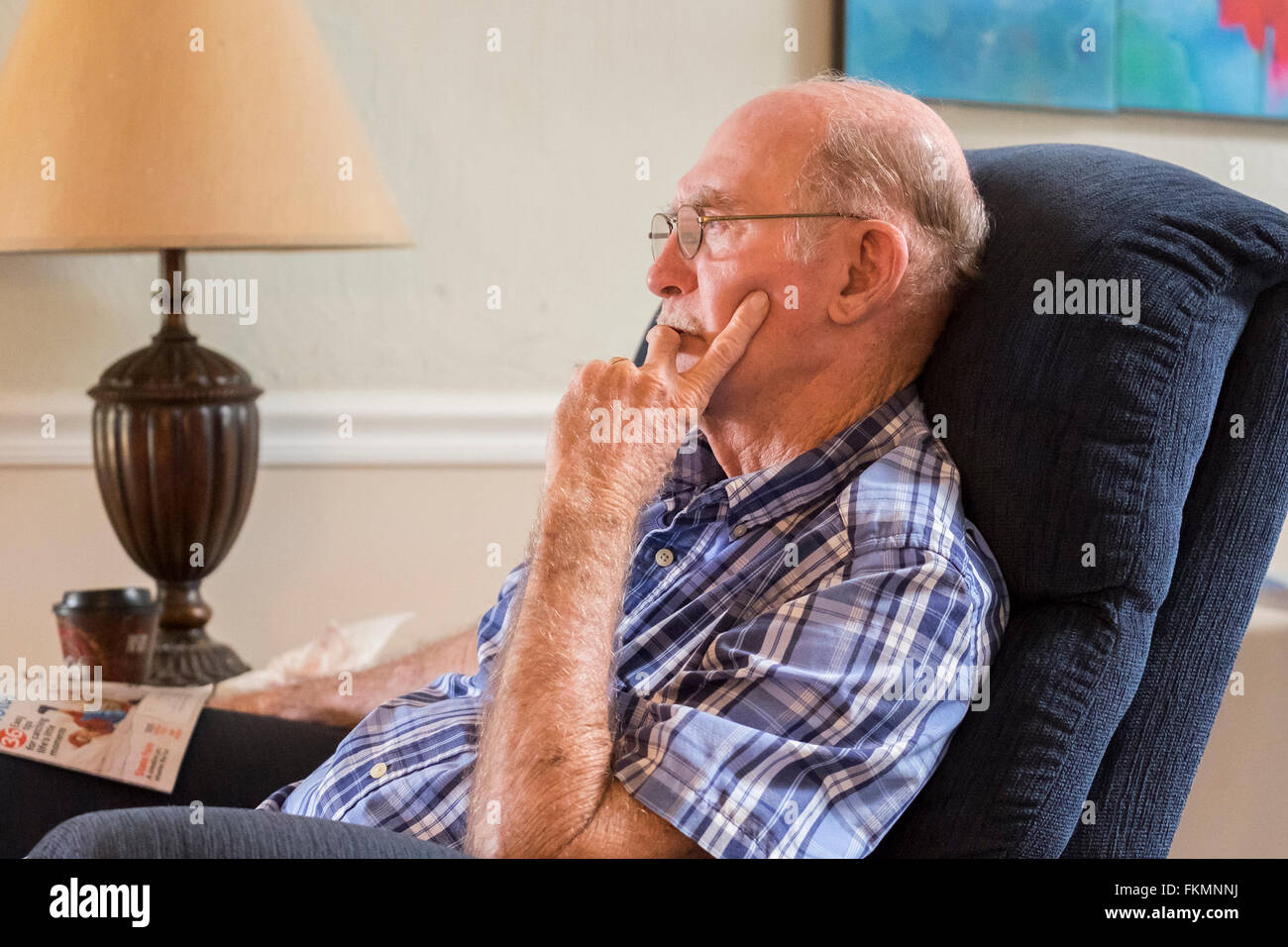 Eine ältere kaukasischen Mann, sitzt in einem Sessel und starrt ins Leere, während leidet unter Demenz und Depression. USA. Stockfoto