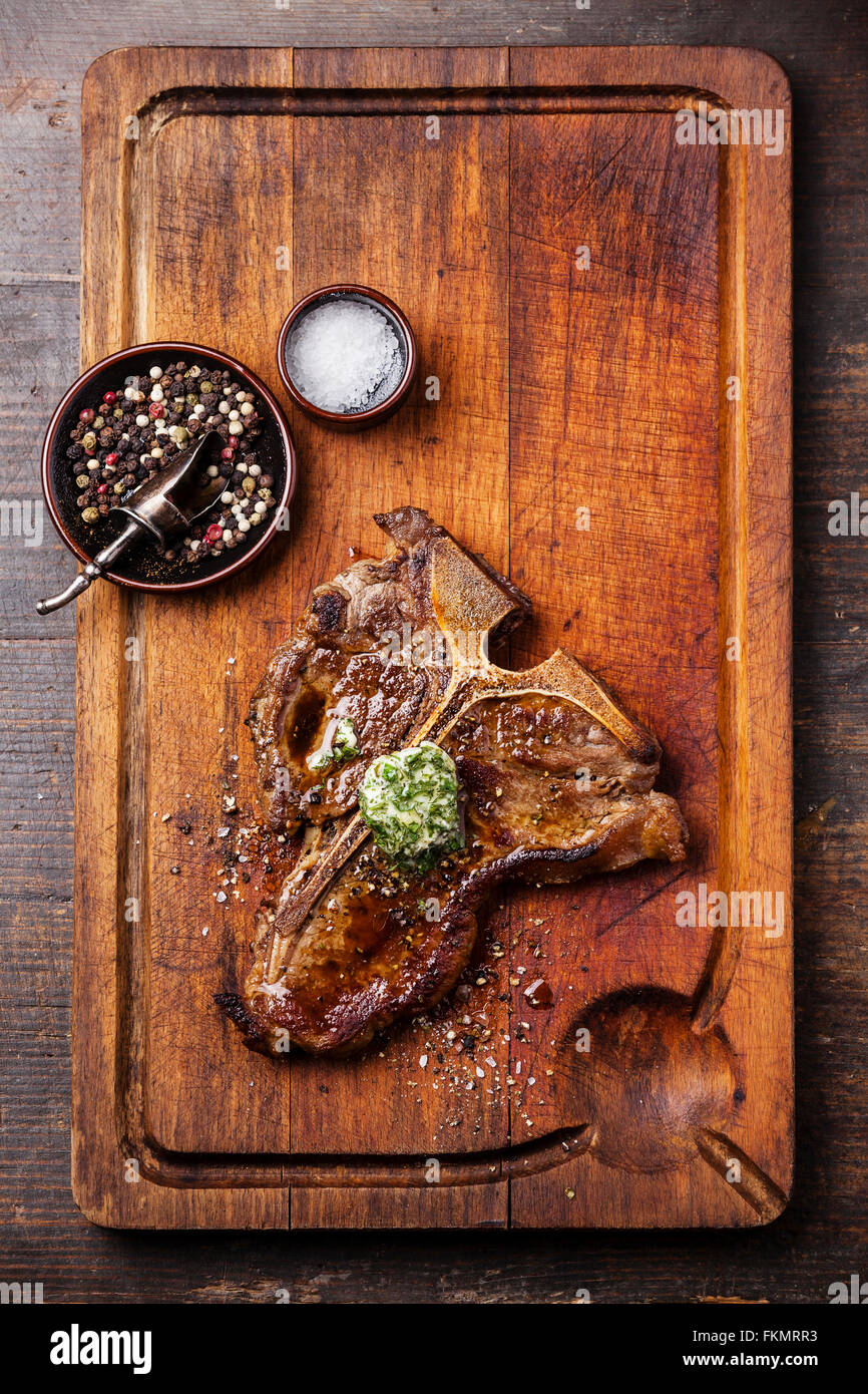Gegrilltes t-Bone Steak und Kräuterbutter auf Holzbrett Stockfoto