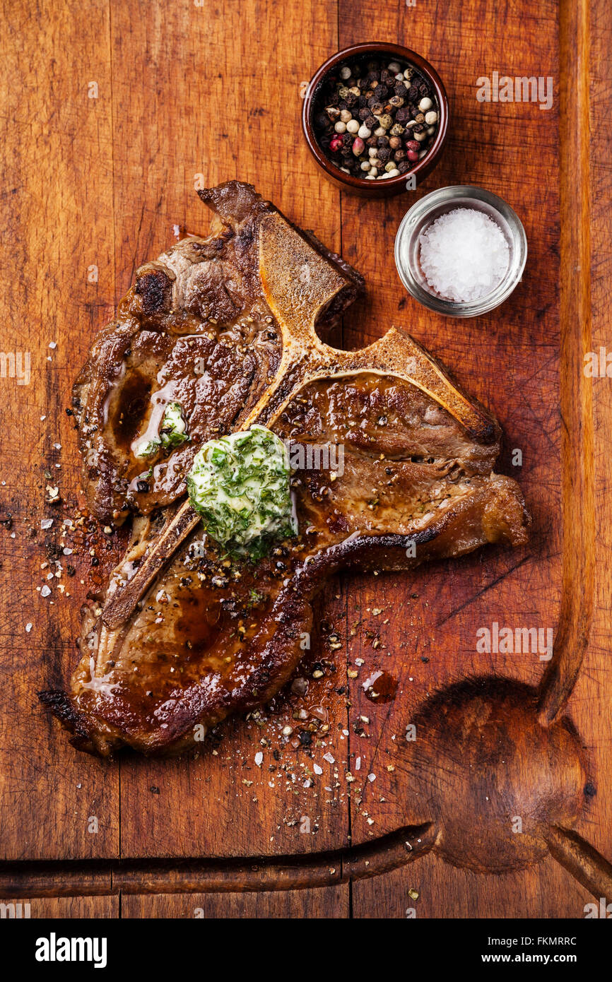 Gegrilltes t-Bone Steak und Kräuterbutter auf Holzbrett Stockfoto