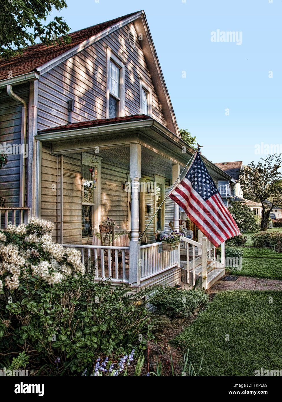 Ein Norman Rockwell inspiriert Bild aus der Vergangenheit mit einer amerikanischen Flagge und einem 90 Jahre alten Haus. Stockfoto
