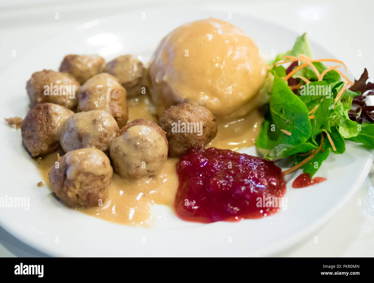 Eine Platte von IKEA Frikadellen, Kartoffelpüree, Sahne Soße, grüner Salat und Preiselbeer-Sauce. Stockfoto