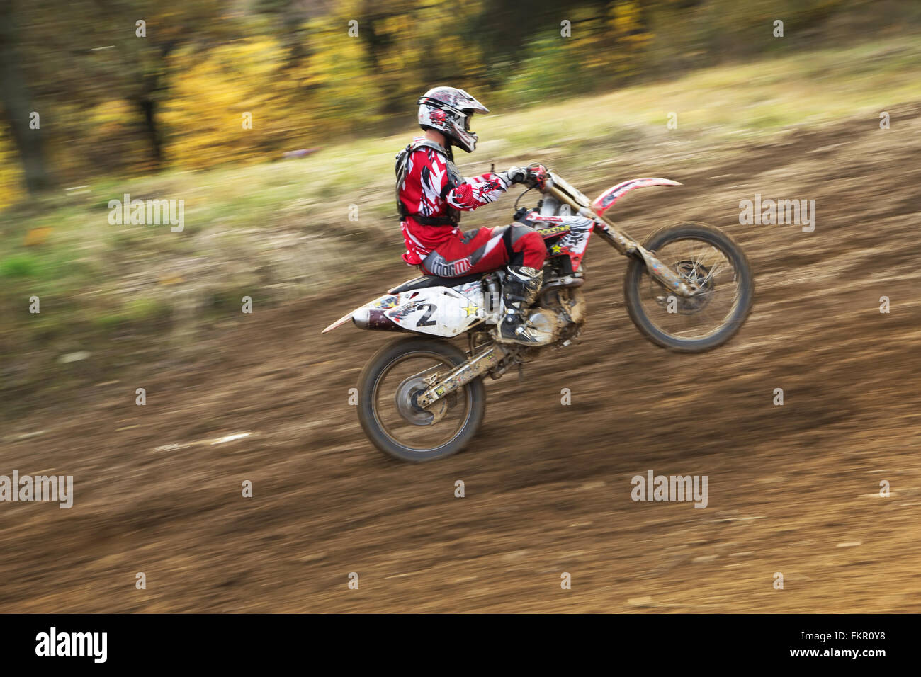 Motocross-Fahrer ist bergauf. Das Vorderrad ist in der Luft. Stockfoto