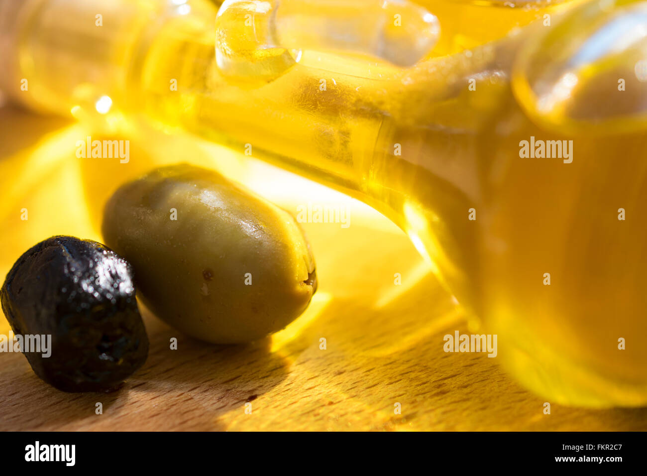 Olivenölflasche mit einigen Oliven Stockfoto
