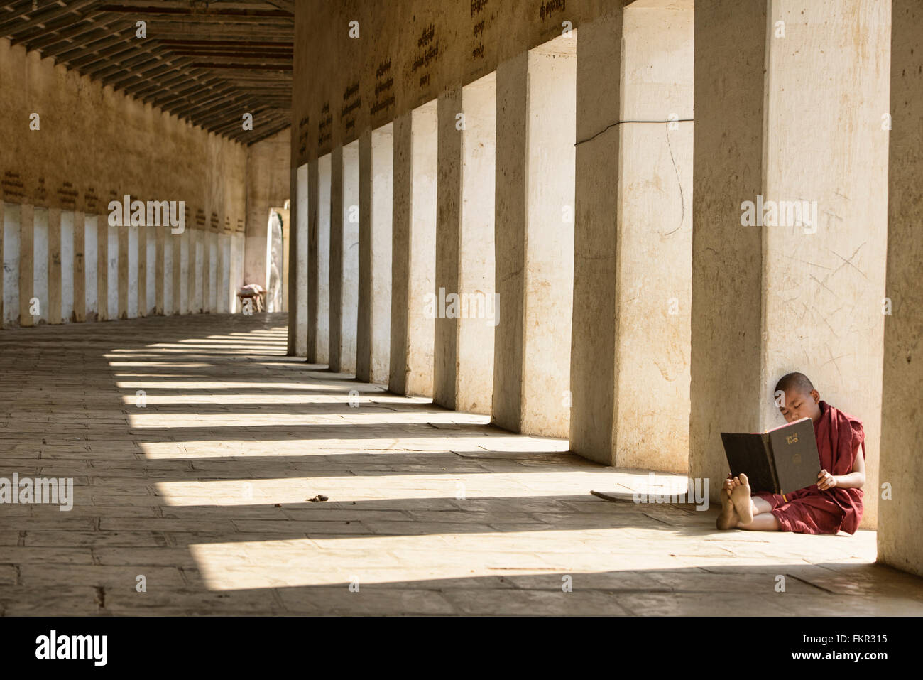 Ein junger Mönch lesen am Eingang zur Shwezagon Pagode in Bagan, Myanmar Stockfoto