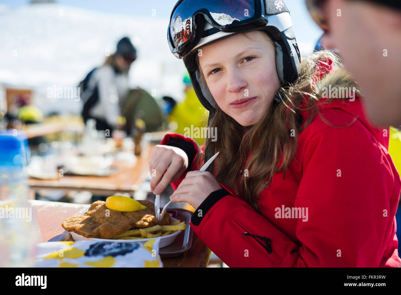 Mädchen in die Kamera Lächeln, wenn Essen Schnitzel mit Pommes in der Mittagspause auf der Ulmer Hütte im Skigebiet St. Anton, Tirol, Österreich Stockfoto