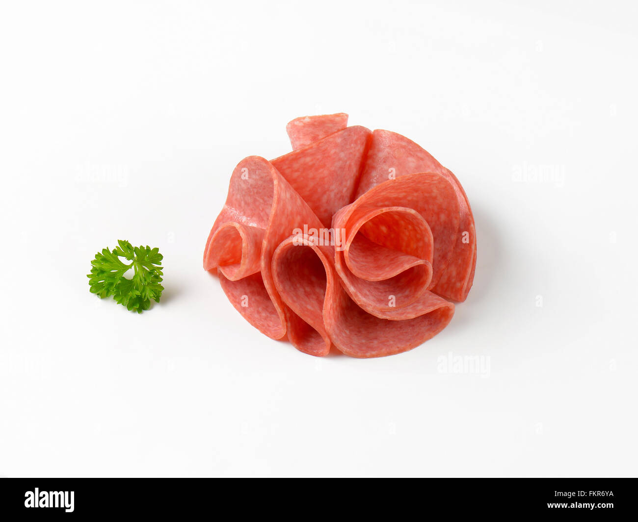 dünne Scheiben Salami auf weißem Hintergrund Stockfoto