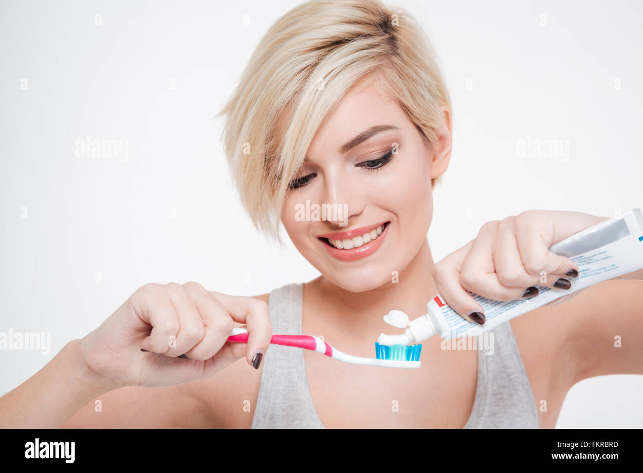 Lächelnde Frau hält eine Zahnbürste und Zahnpasta Platzierung isoliert auf aw Hite background Stockfoto