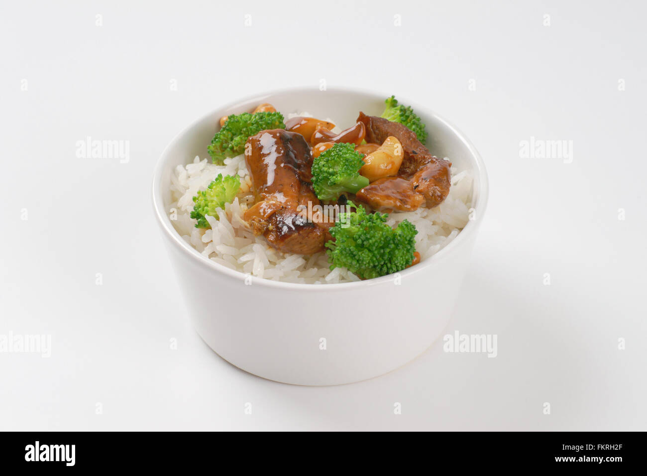 Schüssel Reis mit gebratenem Fleisch und Cashew-Kerne auf weißem Hintergrund Stockfoto