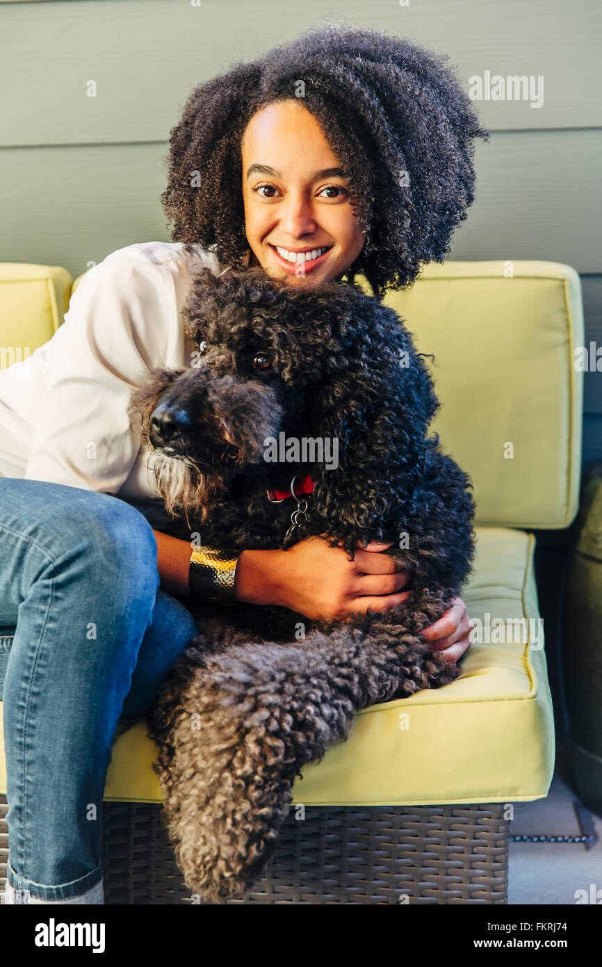 Gemischte Rassen Frau umarmt Hund auf sofa Stockfoto