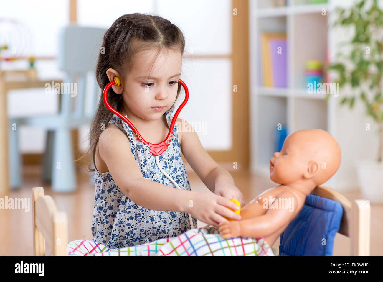 Kind spielt Arzt mit Puppe indoor Stockfoto