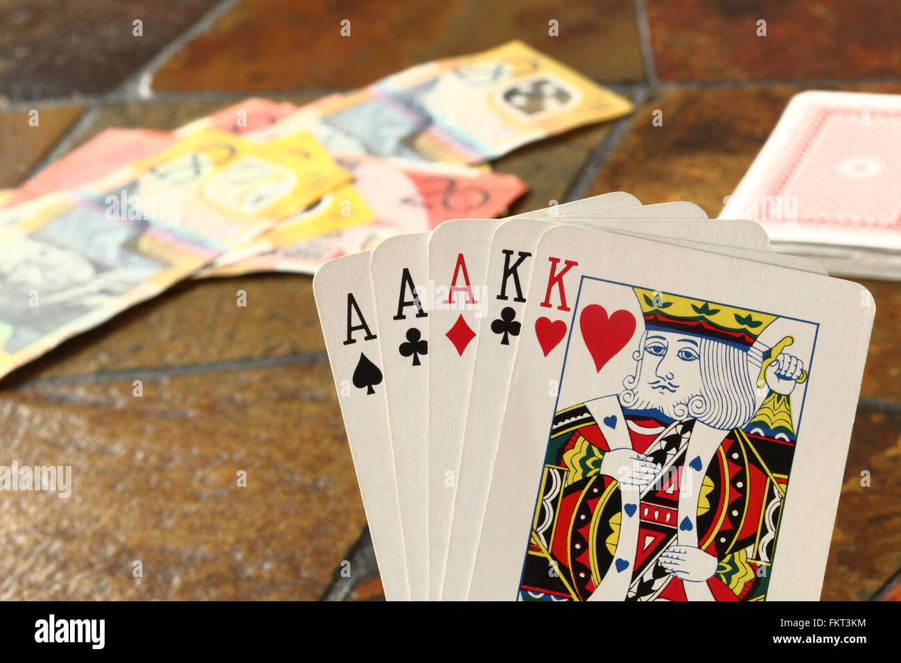 Ein "Full House" Hand von Karten im Vordergrund mit australischen Banknoten einer gekachelten Tischplatte auflegen Stockfoto