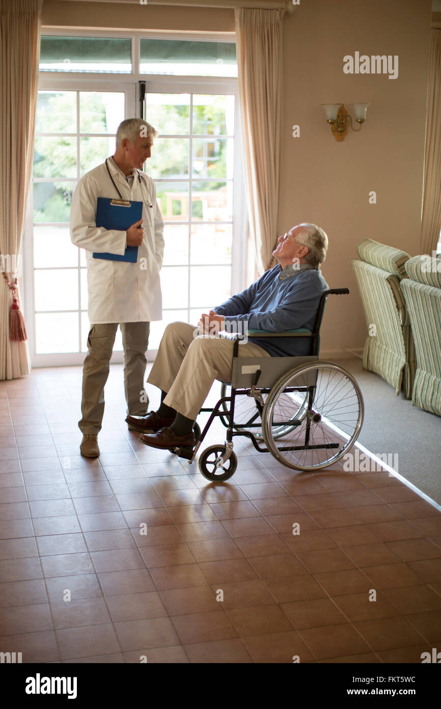 Arzt im Gespräch mit Patienten im Rollstuhl Stockfoto