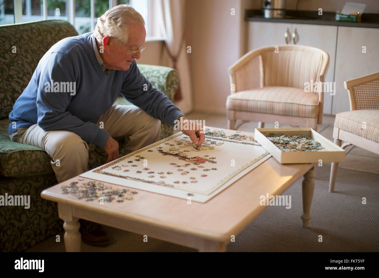 Älterer Mann auf Sofa Lösung puzzle Stockfoto