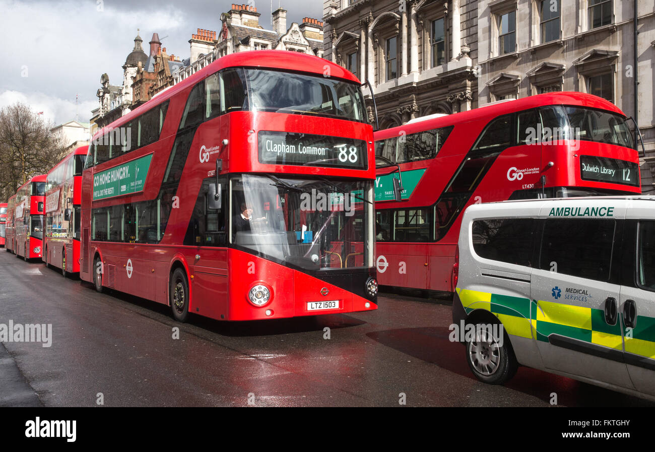 Ikonische roten Londoner Busse in Whitehall in der Nähe von Parlament mit einem Krankenwagen im Vordergrund Stockfoto