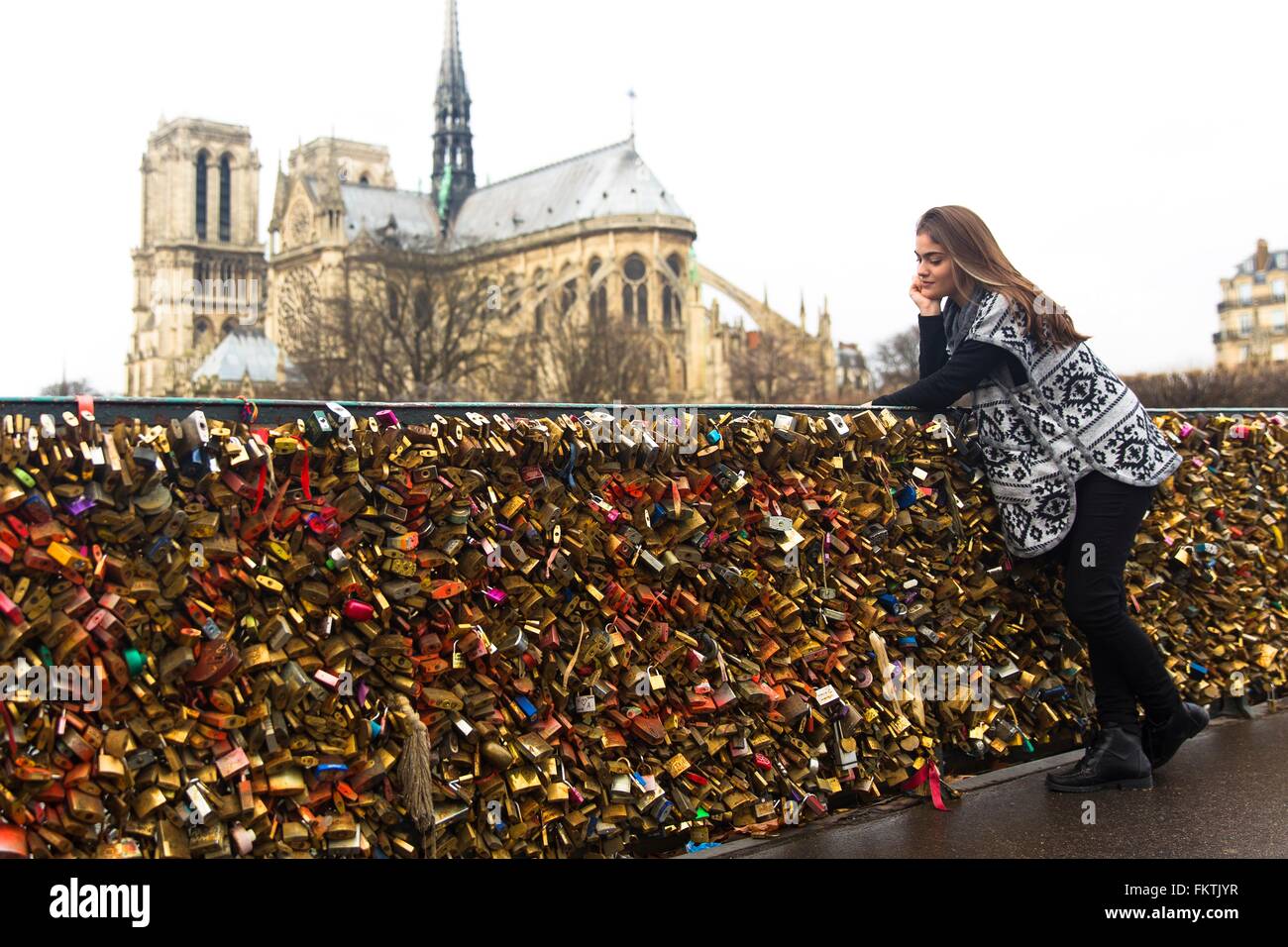 Junge Frau lehnt sich an Liebe Schlösser, Pont de l'archeveche, Notre Dame Kathedrale im Hintergrund, Paris, Frankreich Stockfoto