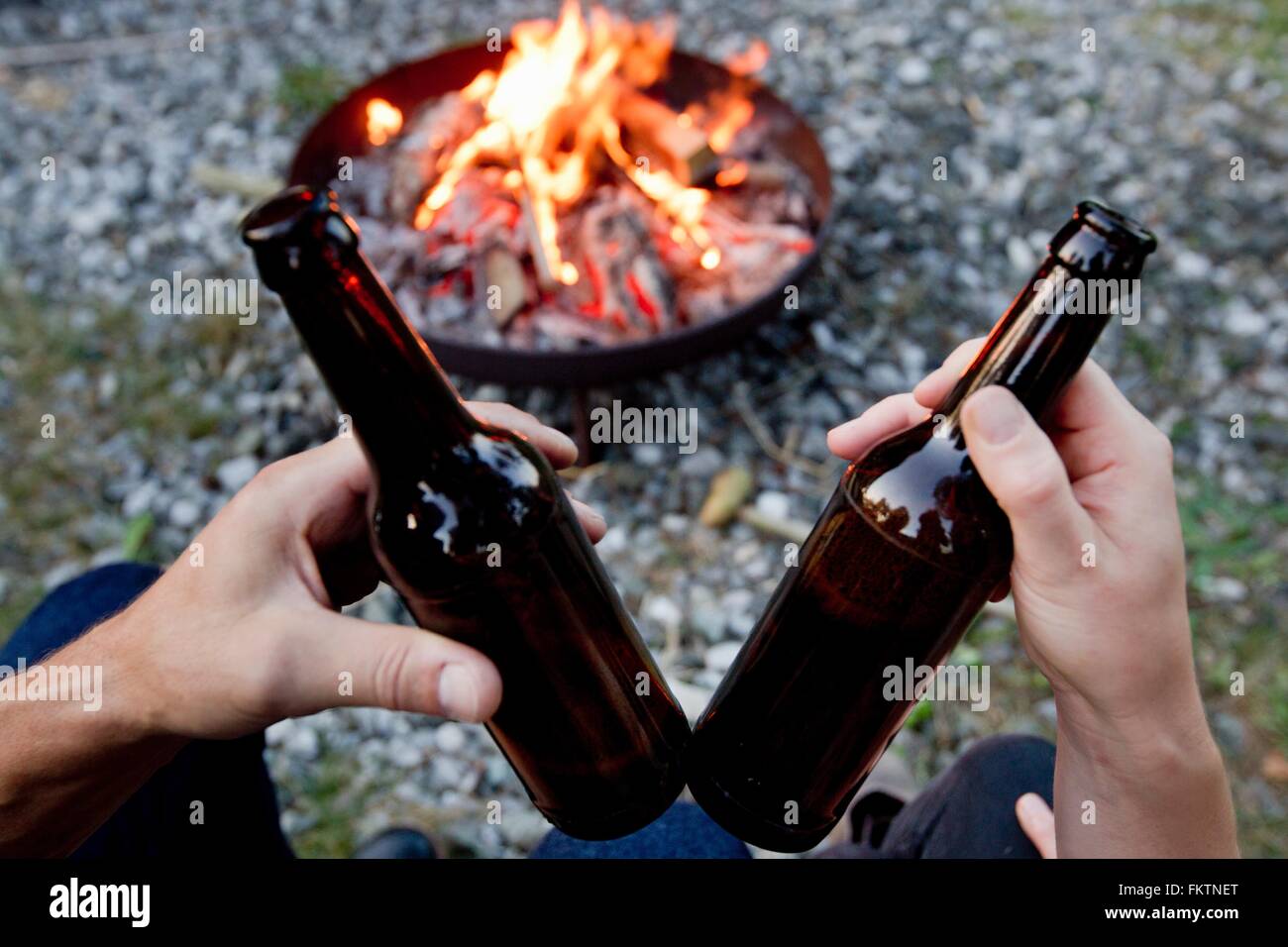 Hände halten Bierflaschen mit Lagerfeuer Stockfoto