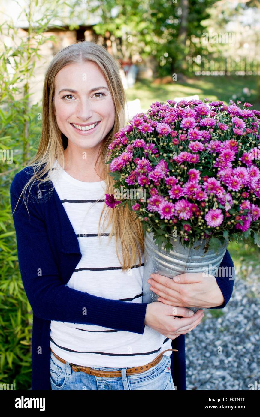 Mitte Erwachsene Frau mit Eimer mit Blumen Stockfoto
