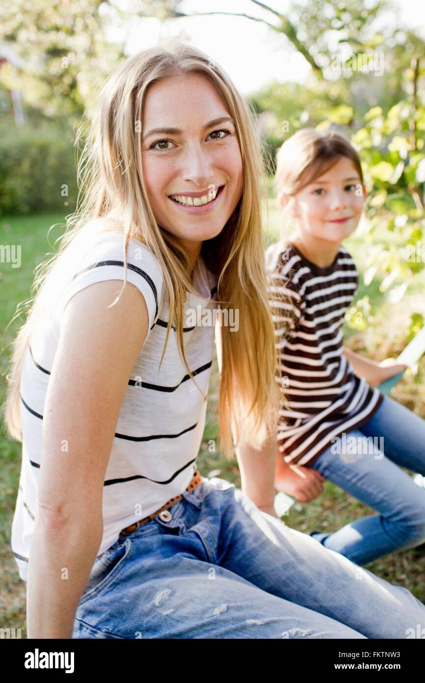 Frau mit langen blonden Haaren, Tochter im Hintergrund Stockfoto