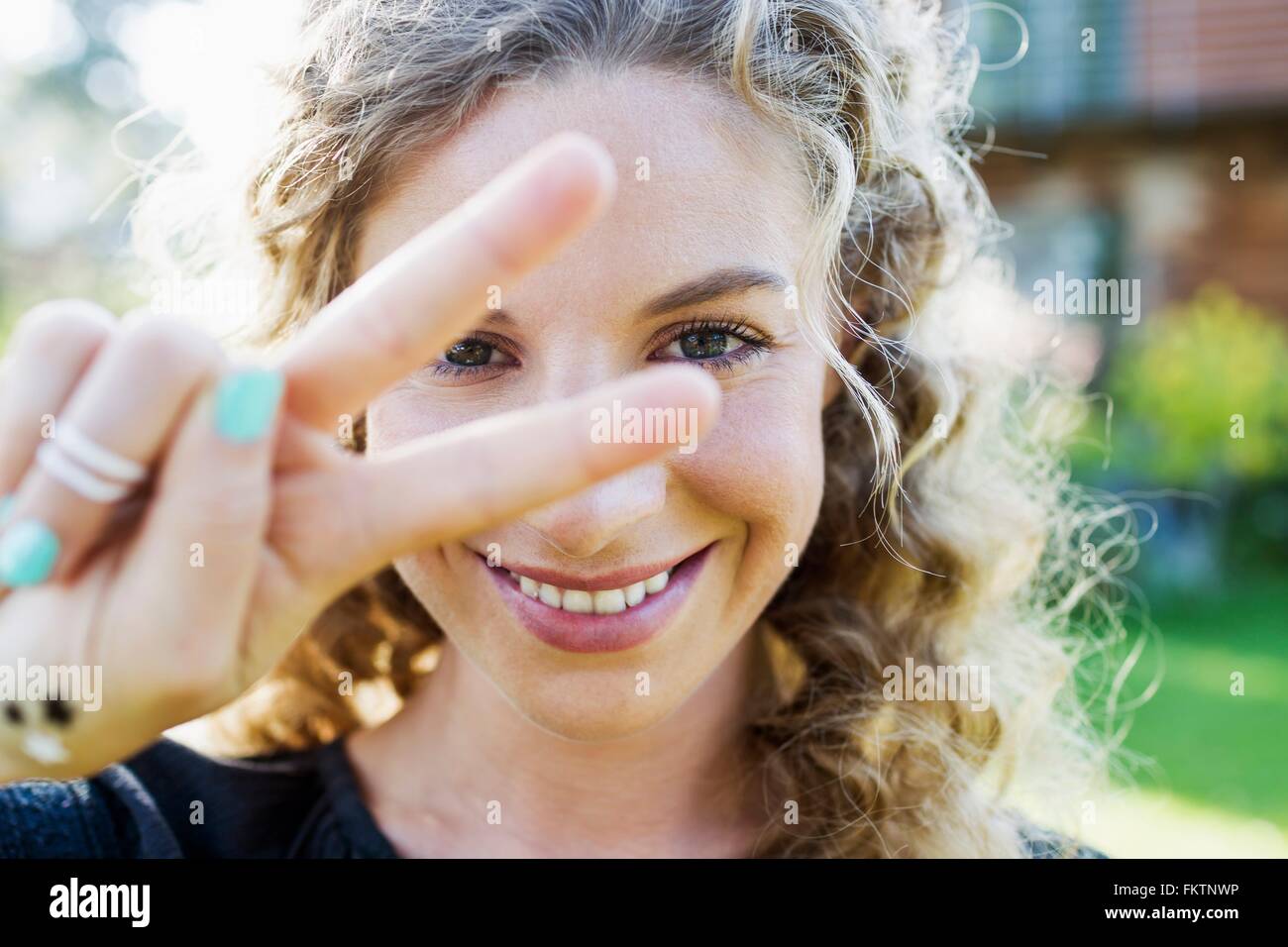 Junge Frau, die Peace-Zeichen mit der Hand machen Stockfoto