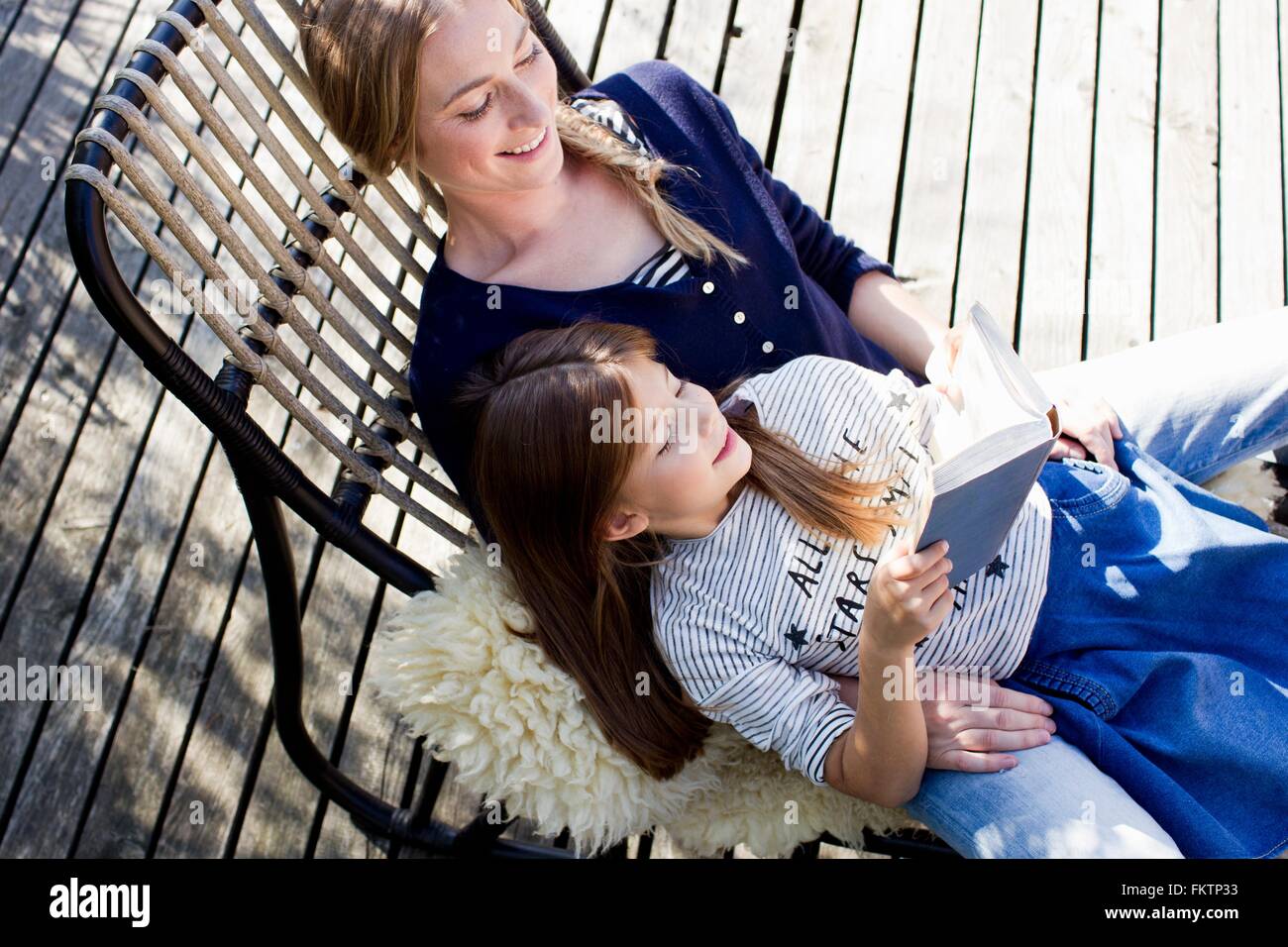 Mutter und Tochter entspannt auf Lounge-Sessel, Mädchen lesen Buch Stockfoto