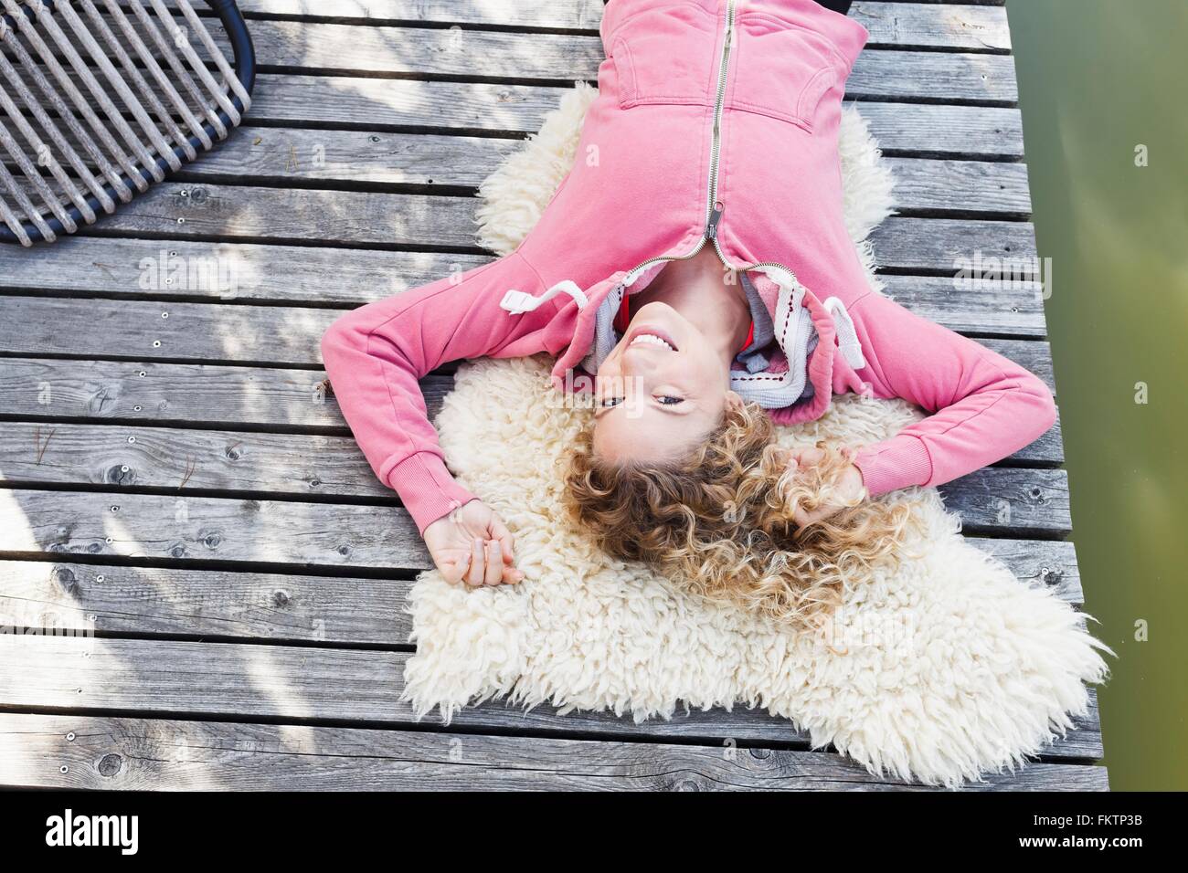Junge Frau liegend auf pelzigen Teppich auf decking, hoher Winkel Stockfoto
