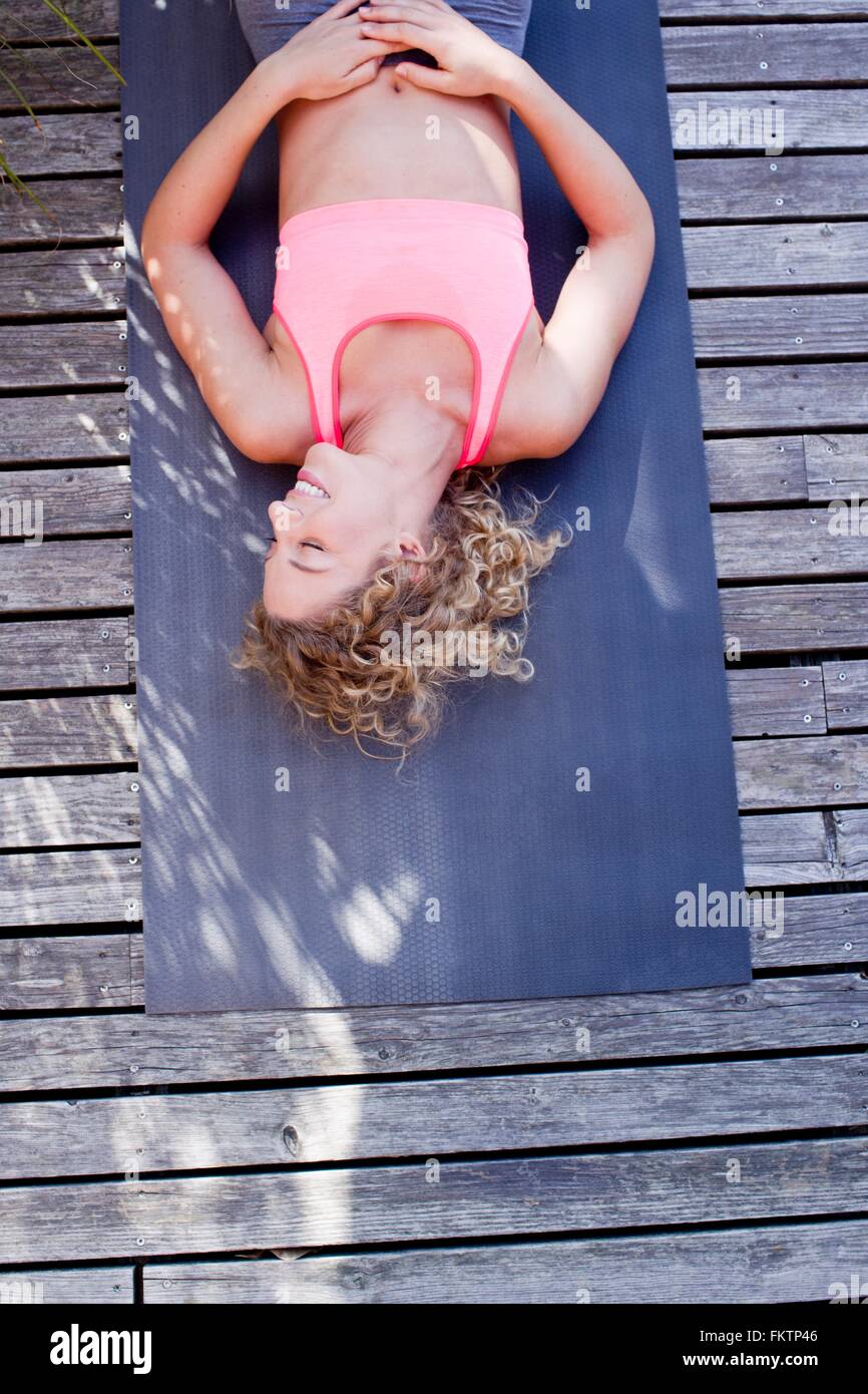 Junge Frau, die auf Yoga-Matte, hoher Winkel liegen Stockfoto