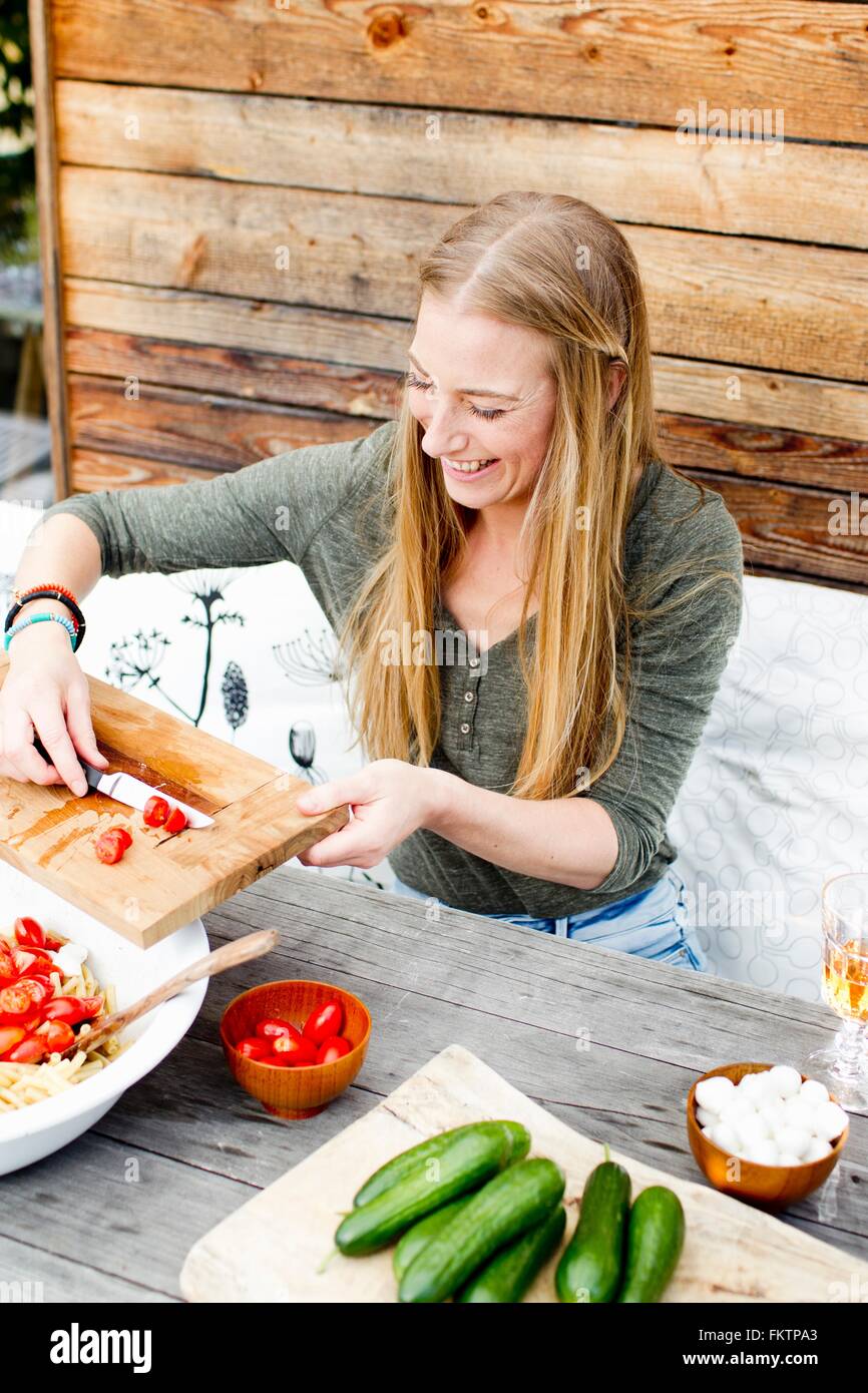 Frau scarping Tomaten in Schüssel aus Schneidebrett Stockfoto