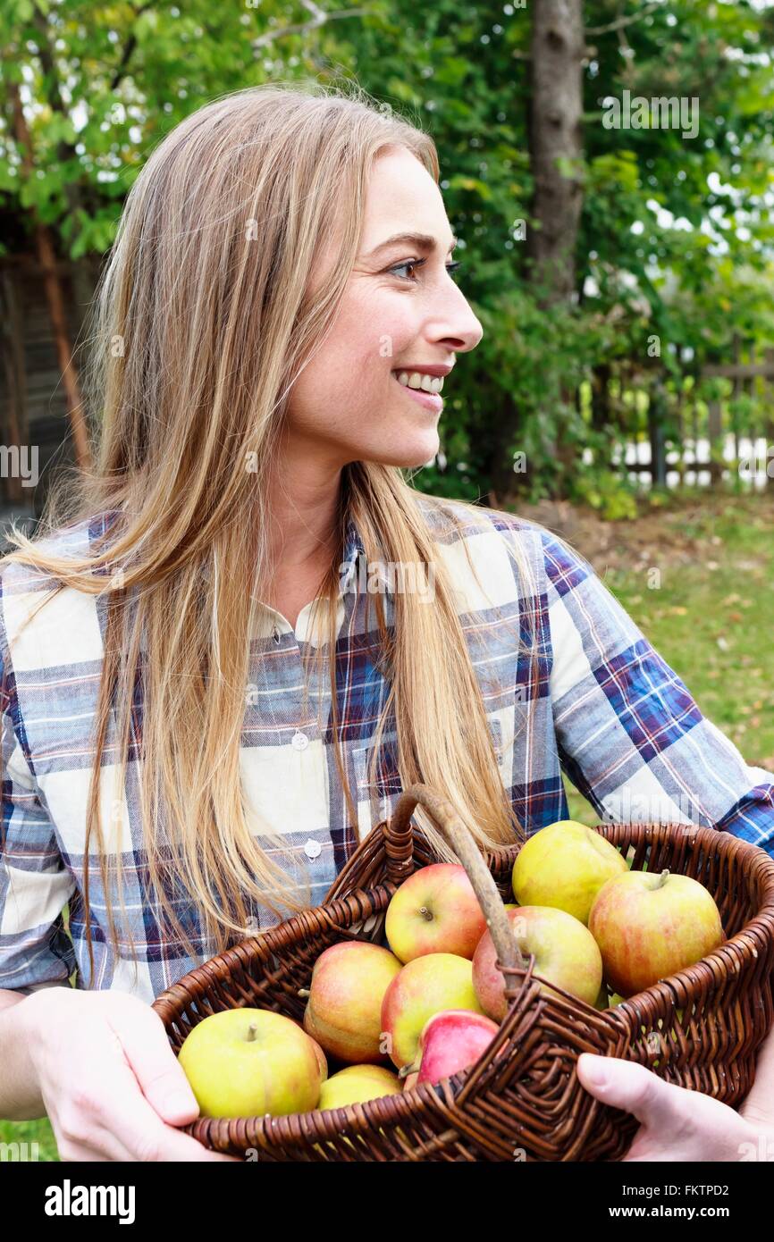Mitte Erwachsene Frau hält Korb einheimische Äpfel Stockfoto