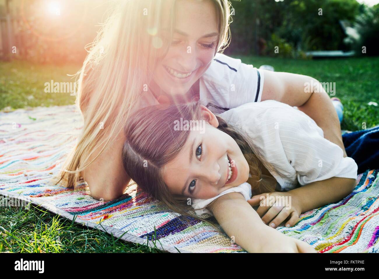 Mutter und Tochter auf Teppich im Garten liegen Stockfoto