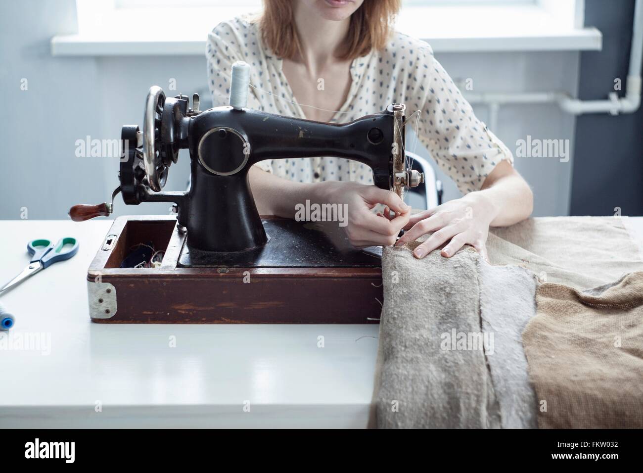 Blick auf Frau Nähen von Textilien auf Vintage Nähmaschine abgeschnitten Stockfoto