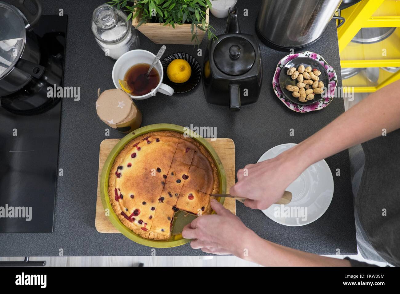 Draufsicht der weiblichen Hand schneiden Kuchen am Küchentisch Stockfoto