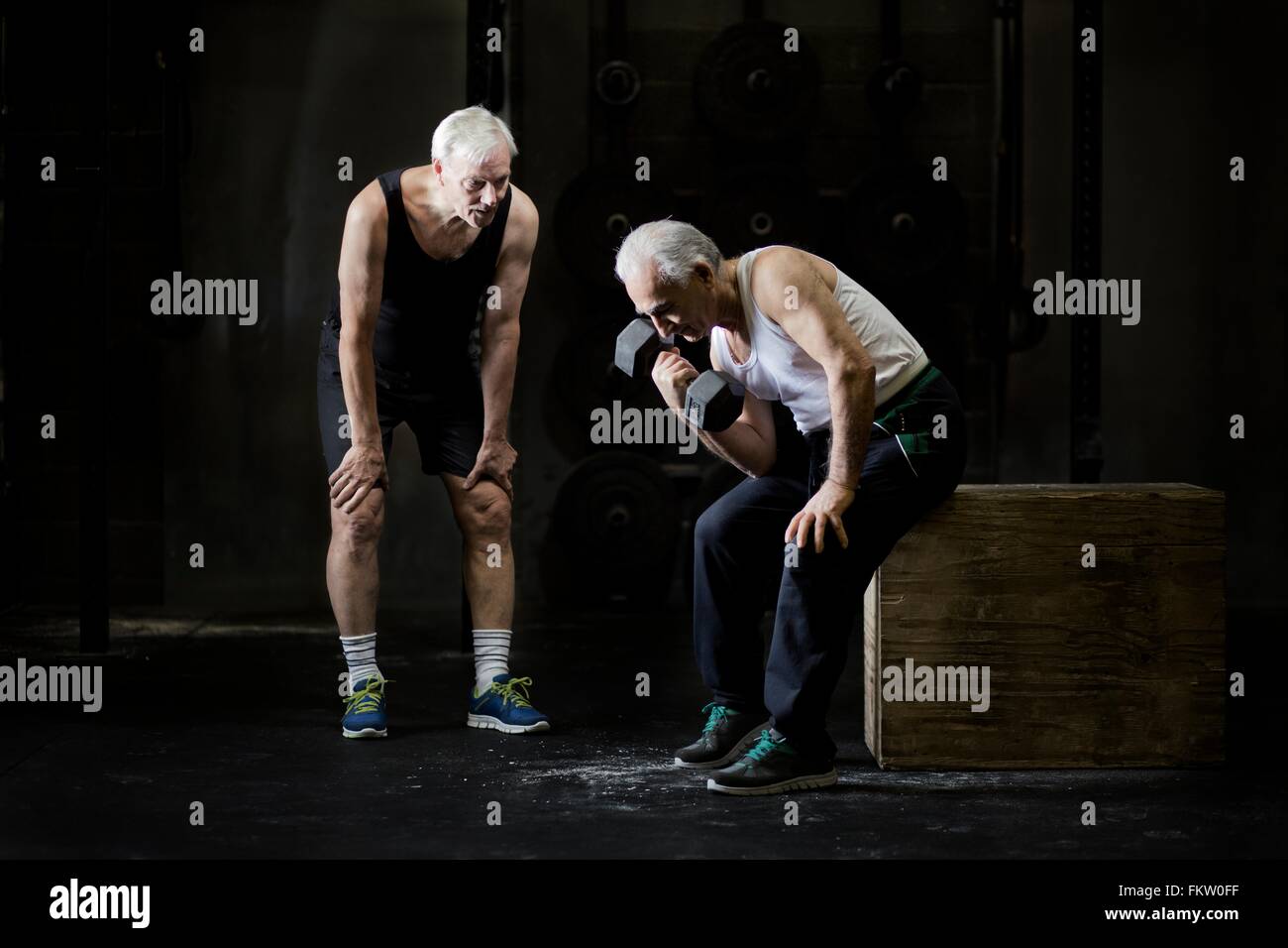 Senioren Herren training mit Hantel in dunklen Turnhalle Stockfoto
