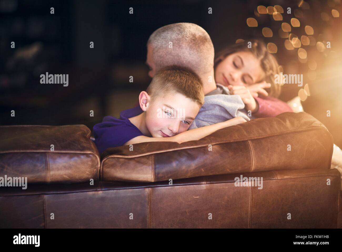 Reifer Mann auf Sofa umarmt Sohn und Tochter Stockfoto