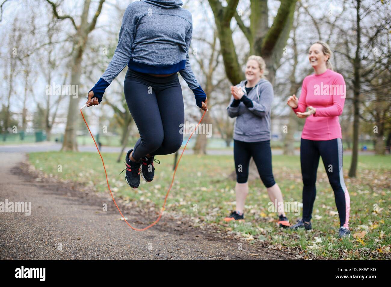 Verkürzten Blick auf junge Frau und Freunden training mit Springseil im park Stockfoto