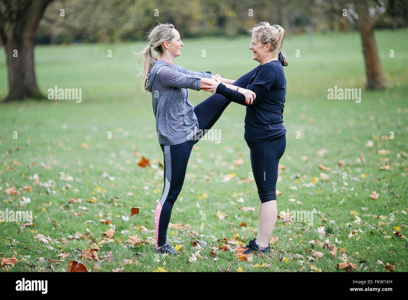 Zwei Frauen, die Aufwärmübungen mit einander im park Stockfoto