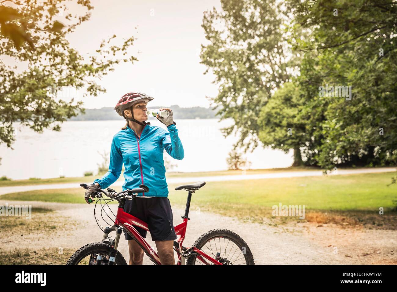 Reifen Mountainbike Frau Trinkwasser am Seeufer Stockfoto