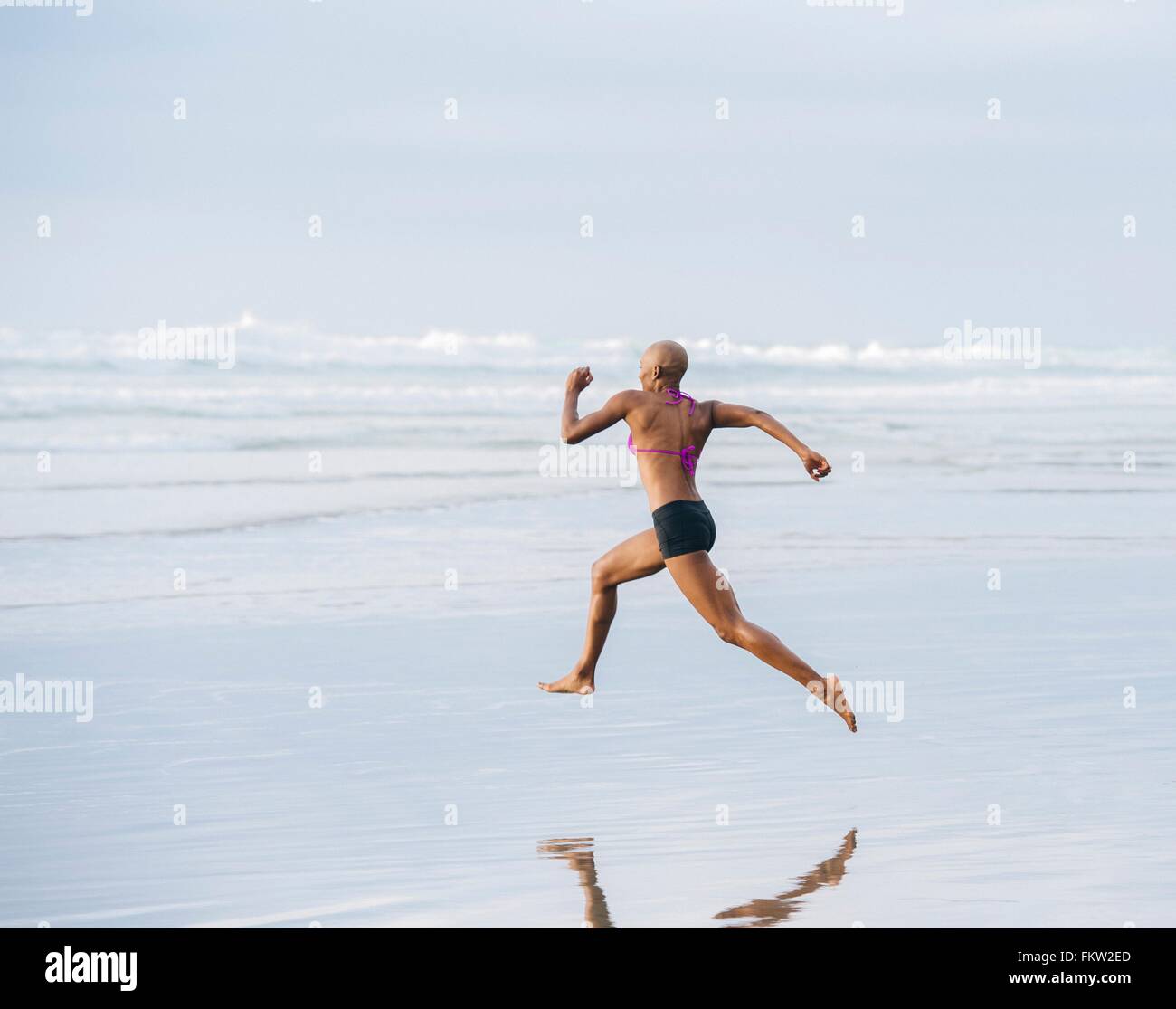 Frau im Bikini am Strand sprinten Stockfoto