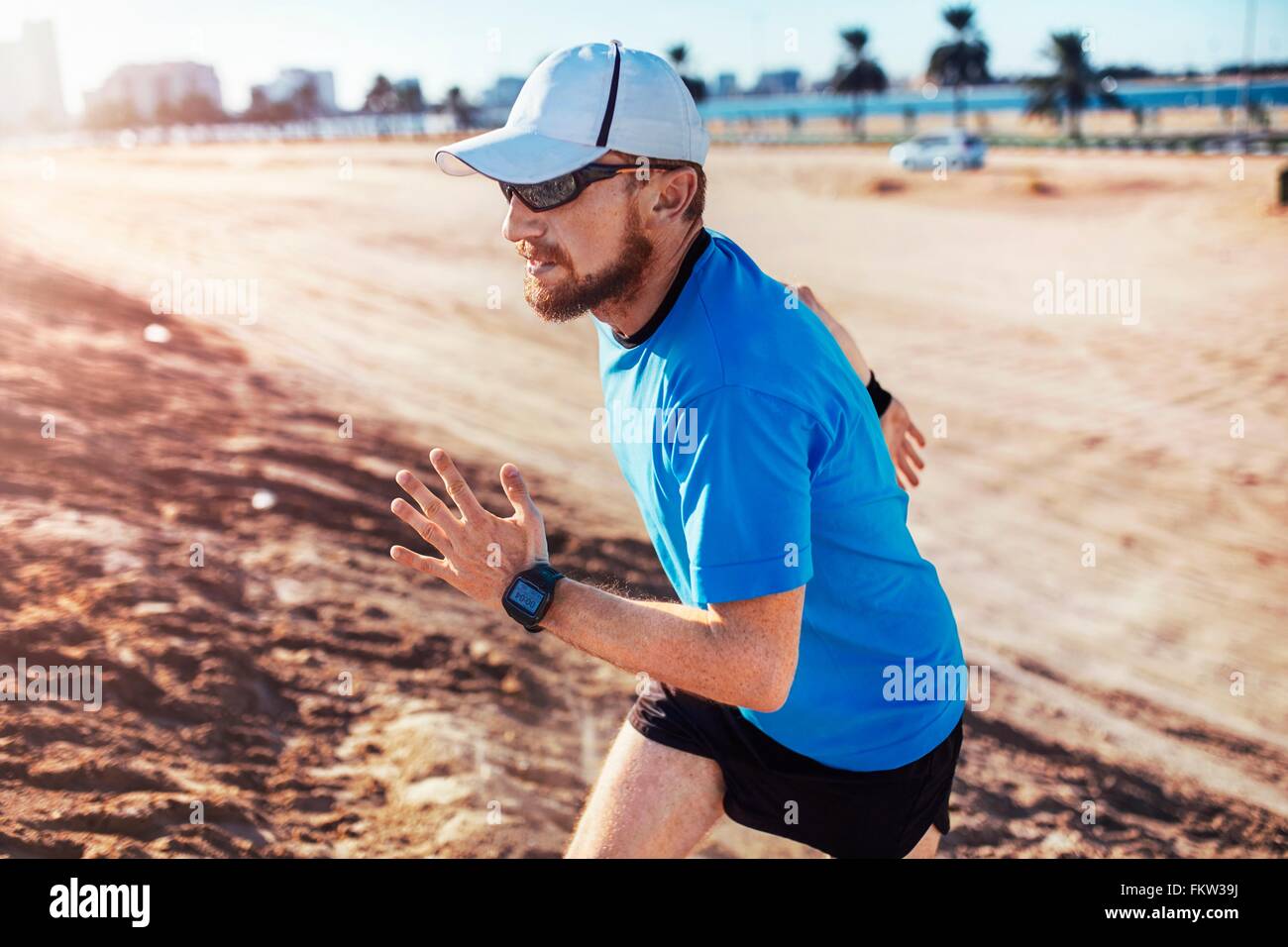 Mitte erwachsener Mann mit Baseballmütze angerannt Sanddüne, Dubai, Vereinigte Arabische Emirate Stockfoto