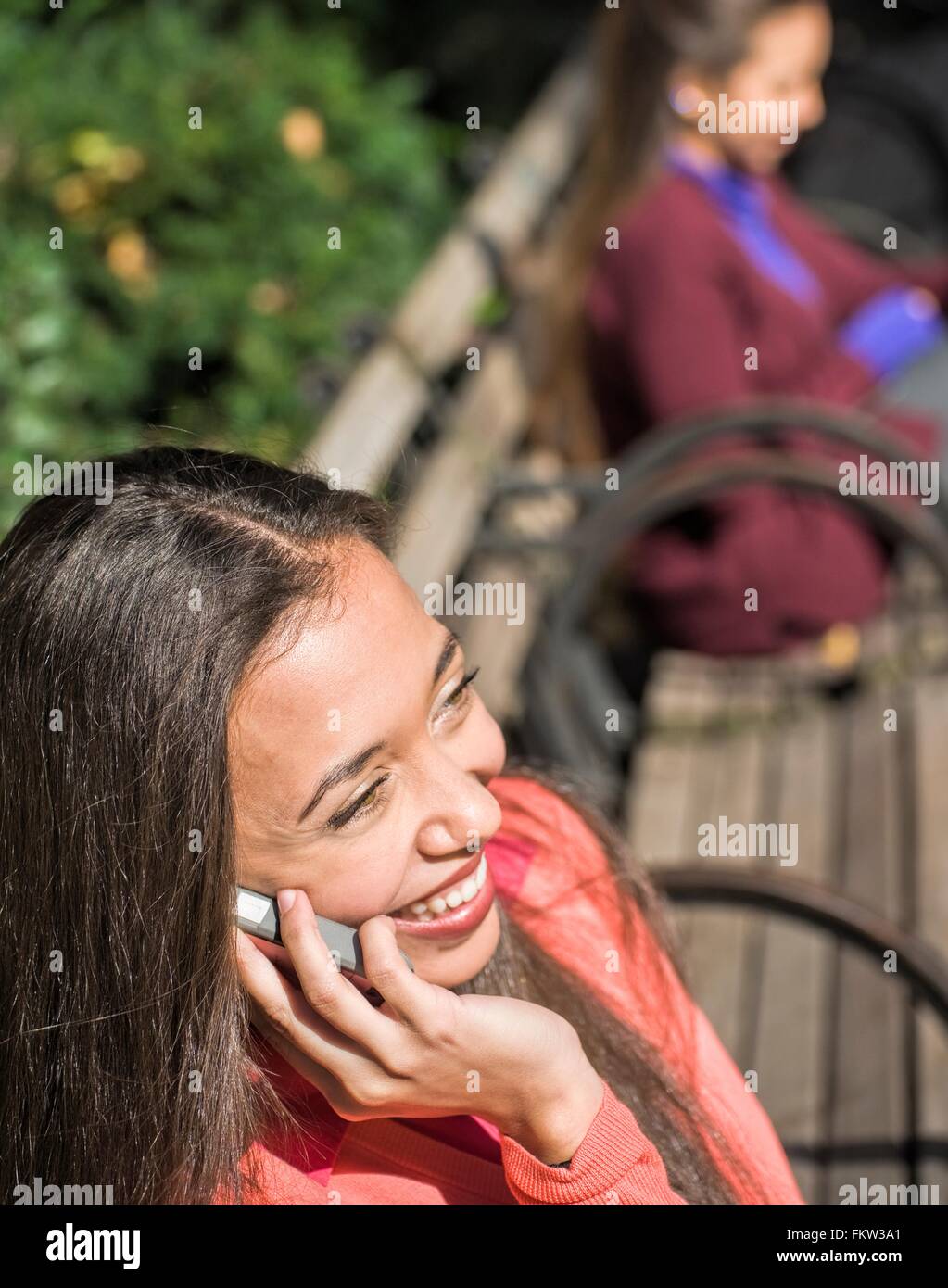 Nahaufnahme von junge Frau sitzt am Park Bench im Chat auf smartphone Stockfoto