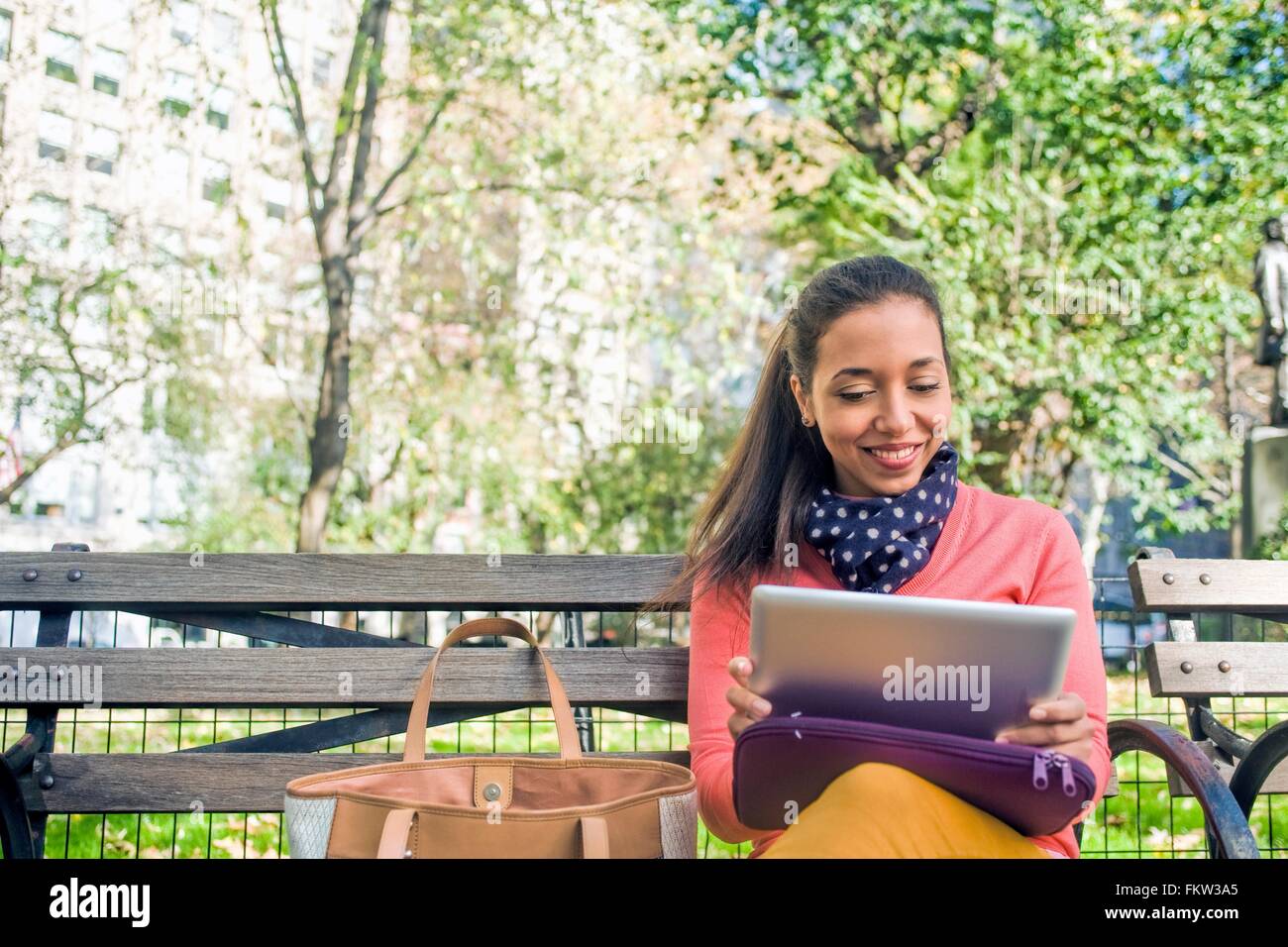 Junge Frau sitzt auf der Parkbank mit digital-Tablette Stockfoto