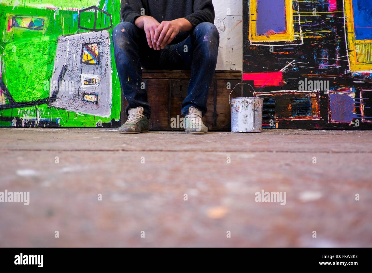 Oberflächenansicht von männlichen Künstler sitzen zwischen Leinwände Stockfoto