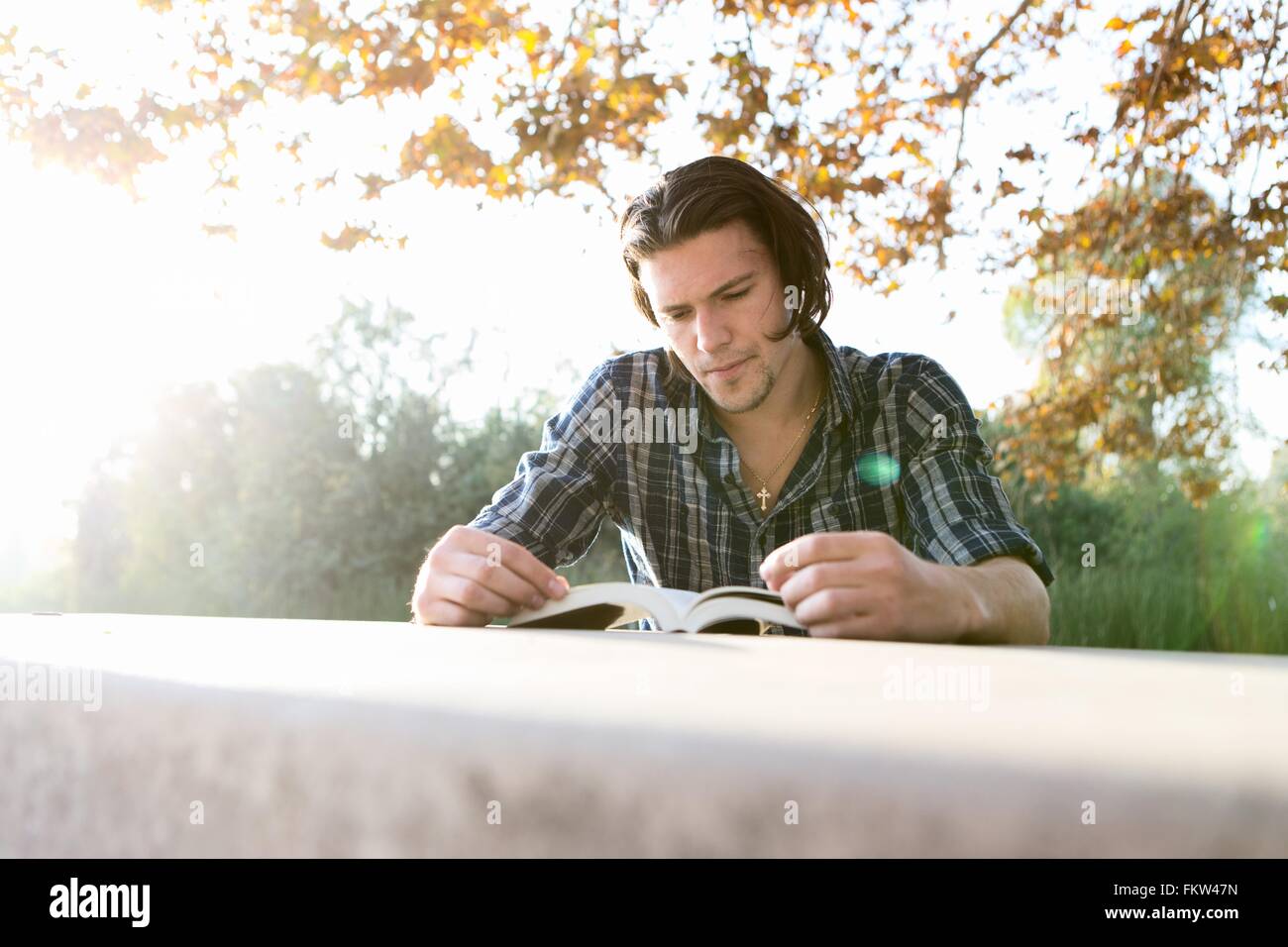 Junger Mann im Freien sitzen am Tisch blickte Buch Stockfoto