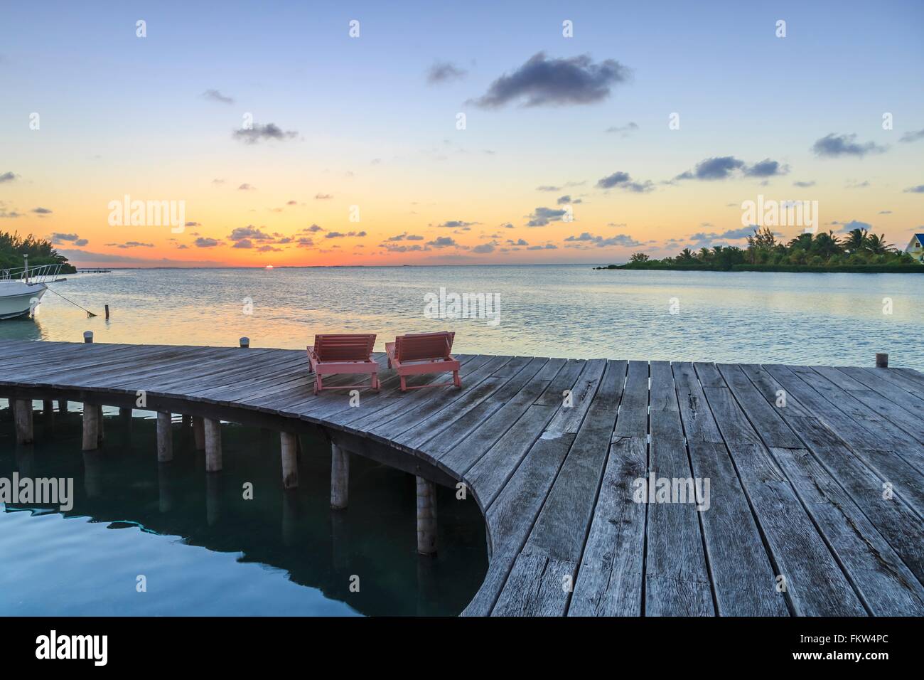 Zwei Liegestühle auf Waterfront Promenade bei Sonnenuntergang, St. Georges Caye, Belize, Mittelamerika Stockfoto