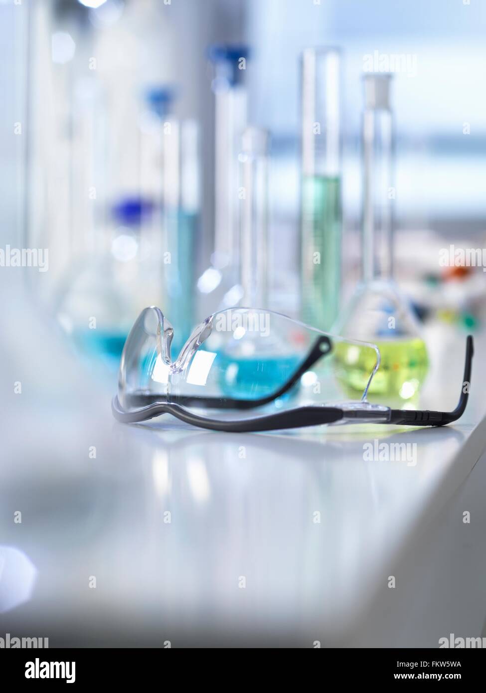 Schutzbrille auf Labortisch, wissenschaftliche Ausrüstung im Hintergrund Stockfoto