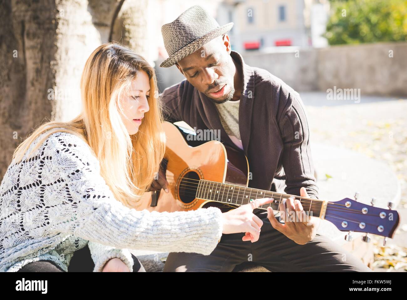 Paar im Park Gitarrespielen lernen Stockfoto