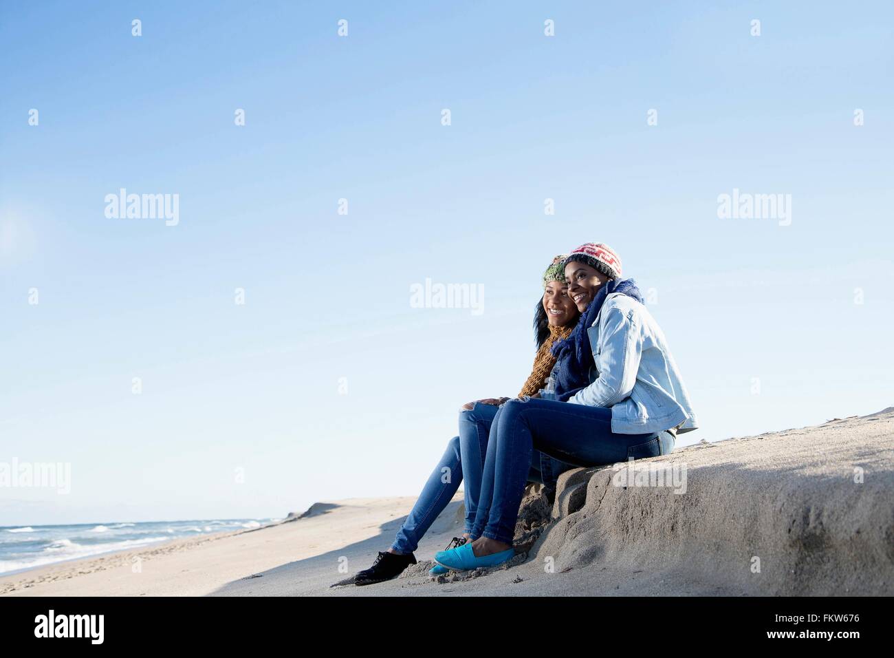 Zwei Freunde sitzen am Strand, betrachten Stockfoto